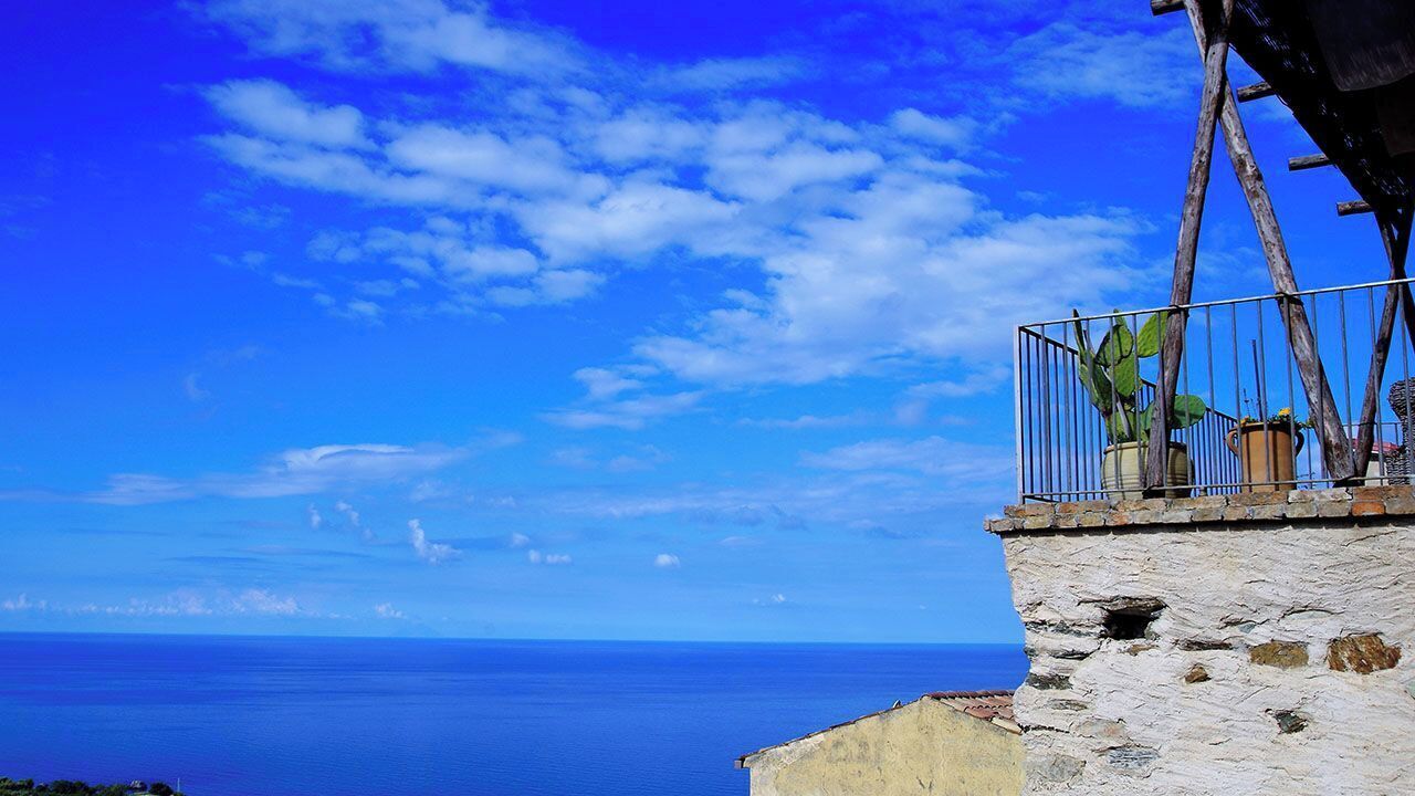 A coastal view with a stone building and a metal railing overlooking the sea.