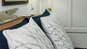 A neatly arranged bedroom with a bed, pillows, a framed picture, and wall-mounted lamps.