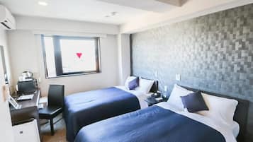 A hotel room with two beds, a desk, a chair, a window with a view, and a textured wall.