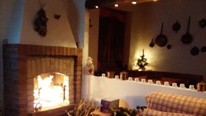 A cozy living room with a brick fireplace, a checkered sofa, and a dining table.