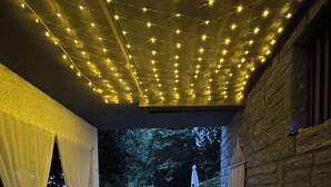 An outdoor seating area with stone flooring, wicker furniture, and string lights.