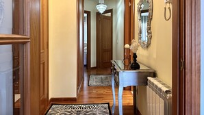 A hallway with wooden doors, a chandelier, a mirror, and a radiator.
