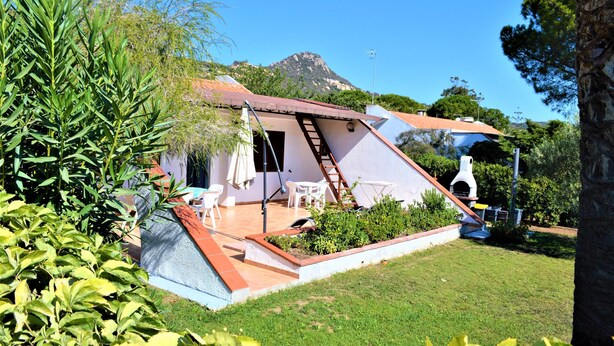 Ein Haus mit einem geneigten Dach, einer Terrasse mit Gartenmöbeln und Blick auf einen Berg.