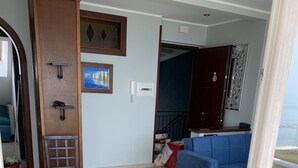 A living room with a blue sofa, a wooden chair, and a tiled floor.