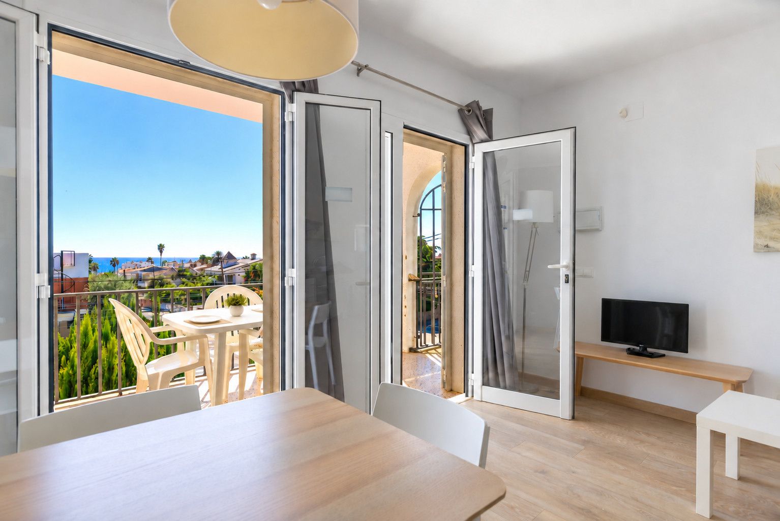 A modern room with a balcony, a dining area, and a TV.