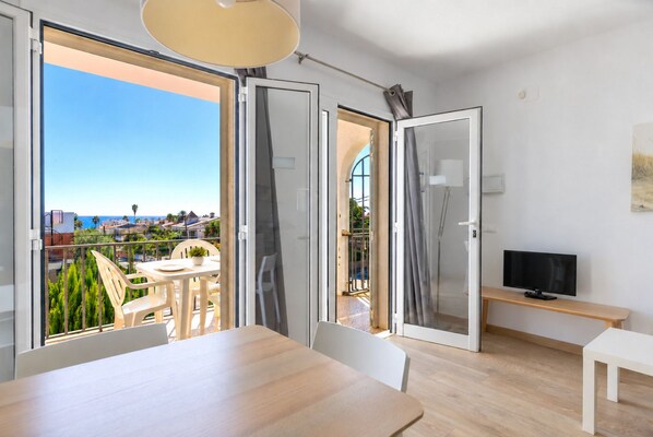 A modern room with a balcony, a dining area, and a TV. - Lovely & Quiet Apartment near the Beach · UHC ACACIAS 120 (Cambrils)