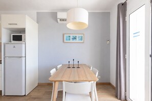 Eine kleine Küche mit einer Mikrowelle, einem Kühlschrank und einem Esstisch mit Stühlen.