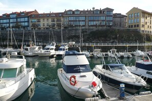 A marina with multiple boats docked, a stone wall, and buildings in the background.