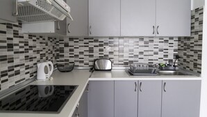 Une cuisine moderne avec des meubles gris, un dosseret carrelé en noir et blanc et des appareils électroménagers en acier inoxydable.