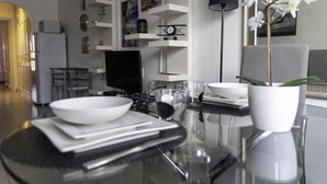 Une cuisine moderne avec une table à manger au plateau en verre, des meubles blancs et un lampadaire noir.