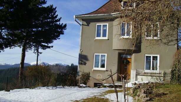 A two-story house with a sloped roof, multiple windows, and a front porch. - Lovingly furnished attic vacation apartment in Vosges house (up to 4 people maximum) (Hohrod)