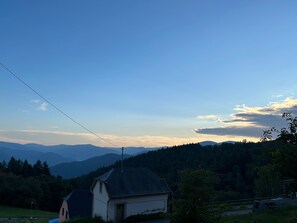 A rural landscape with a house, a power line, and a forested mountain range. - Beautiful apartment in a huge house in the Vosges (Hohrod)