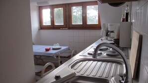 A kitchen with a sink, a window, and a table with a checkered tablecloth. - Lovingly furnished attic vacation apartment in Vosges house (up to 4 people maximum) (Hohrod)