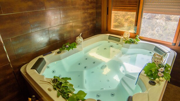 Una stanza spa con una grande vasca da bagno, pareti in legno e una finestra.