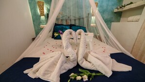 Un letto a baldacchino, un bouquet di fiori e due asciugamani a forma di cigno.