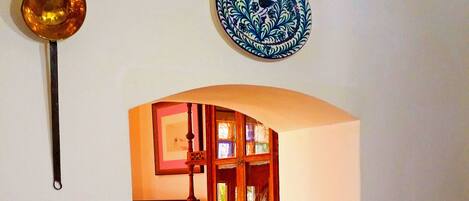 A dining area with a table set for two, a television in the background, and a kitchen visible through an archway.