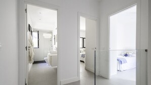 Een lichte, open woonkamer in een hotel met een badkamer, slaapkamer en gang.