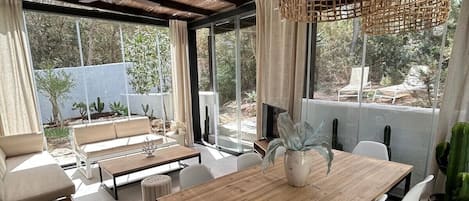 A modern dining area with a wooden table, white chairs, and a ceiling fan.