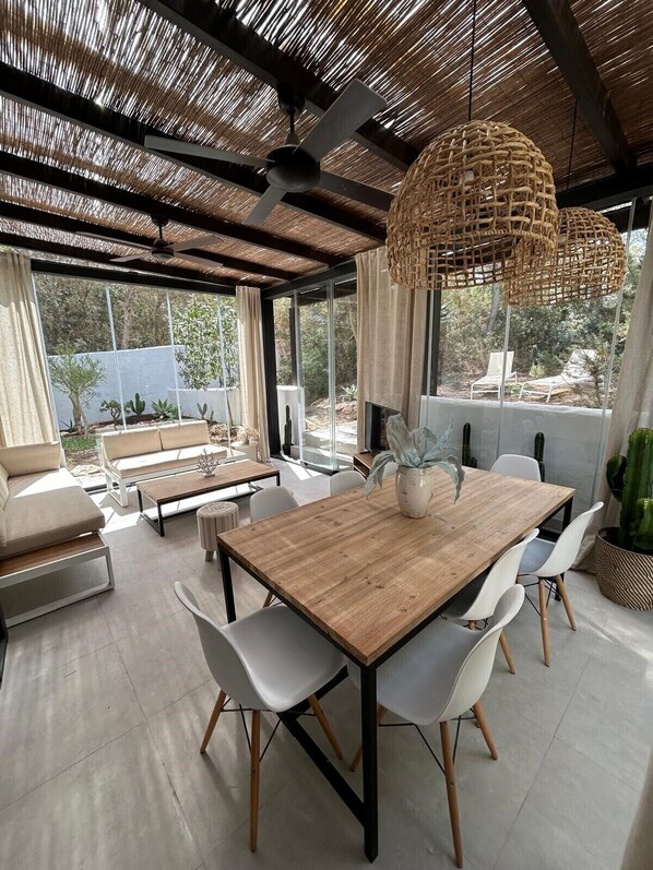 A modern dining area with a wooden table, white chairs, and a ceiling fan.