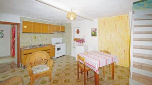 Eine kleine Küche mit Holzausbau, einem weißen Herd und einem Essbereich mit gestreiftem Tischlein.