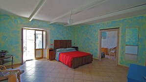 Ein Schlafzimmer mit einem Bett, einem Nachttisch, einem Sessel und einem Fenster.