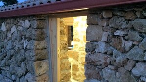 A stone building with a wooden door leading to an interior space. - House Mmiriusa (Noto)