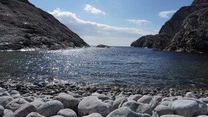 En klippig kustlinje med klart vatten och utsikt över havet.