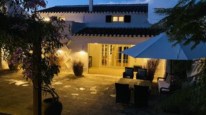 An outdoor patio area with a table and chairs, potted plants, and a large umbrella. - Magnificent country house with private pool, free WiFi (Sant Climent)