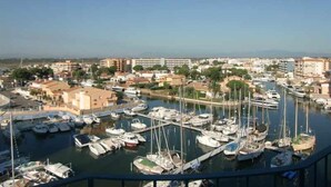 Un port de plaisance où sont amarrés de nombreux bateaux, entouré de bâtiments et de verdure.