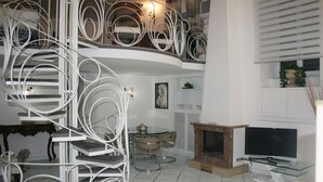 Un intérieur moderne agrémenté d’un escalier en colimaçon, d’une cheminée, d’un téléviseur à écran plat et d’un coin repas.