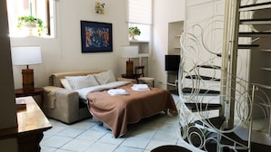 Une chambre d’hôtel moderne équipée d’un lit, d’un canapé, d’une télévision et d’un escalier en colimaçon original.