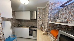 Une petite cuisine équipée d’une cuisinière, d’un four et d’un évier, le tout entouré de carreaux décoratifs.
