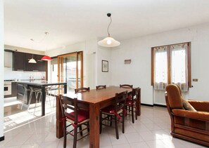 A modern kitchen with dark cabinets, a central island, and a dining area with a wooden table and chairs. - APARTMENT VITTORIO, 2 bathroom, 2 bedrooms, near Venice, Prosecco area Cortina  (Vittorio Veneto)