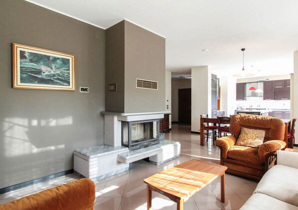 A living room with a fireplace, a dining area, and a kitchen in the background. - APARTMENT VITTORIO, 2 bathroom, 2 bedrooms, near Venice, Prosecco area Cortina  (Vittorio Veneto)