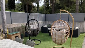 A patio area with a table, chairs, and two hanging chairs.