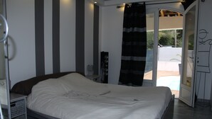 A bedroom with a bed, a bedside table, a lamp, and a window with curtains.