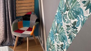 A room with teal walls, a wooden slat wall decor, a dreamcatcher, and a chair with a colorful cushion.