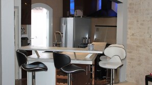 A modern kitchen with a bar area, stainless steel appliances, and black and white bar stools.