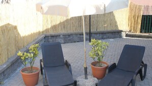 Two lounge chairs, a potted plant, and a white umbrella in an outdoor seating area. - Casa Vacanza Etna - A OASI OF PEACE AND SERENITY (Linguaglossa)