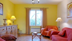 A living room with a sofa set, a table, a cabinet, and a window with curtains. - Vineyard cottage classified 4* with large pool between Carcassonne and Narbonne (Ferrals-Les-Corbières)