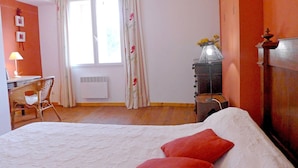 A bedroom with a bed, a desk, a chair, a radiator, and a window with curtains. - Vineyard cottage classified 4* with large pool between Carcassonne and Narbonne (Ferrals-Les-Corbières)