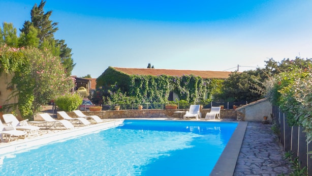 A swimming pool with white lounge chairs and a stone pathway. - Vineyard cottage classified 4* with large pool between Carcassonne and Narbonne (Ferrals-Les-Corbières)