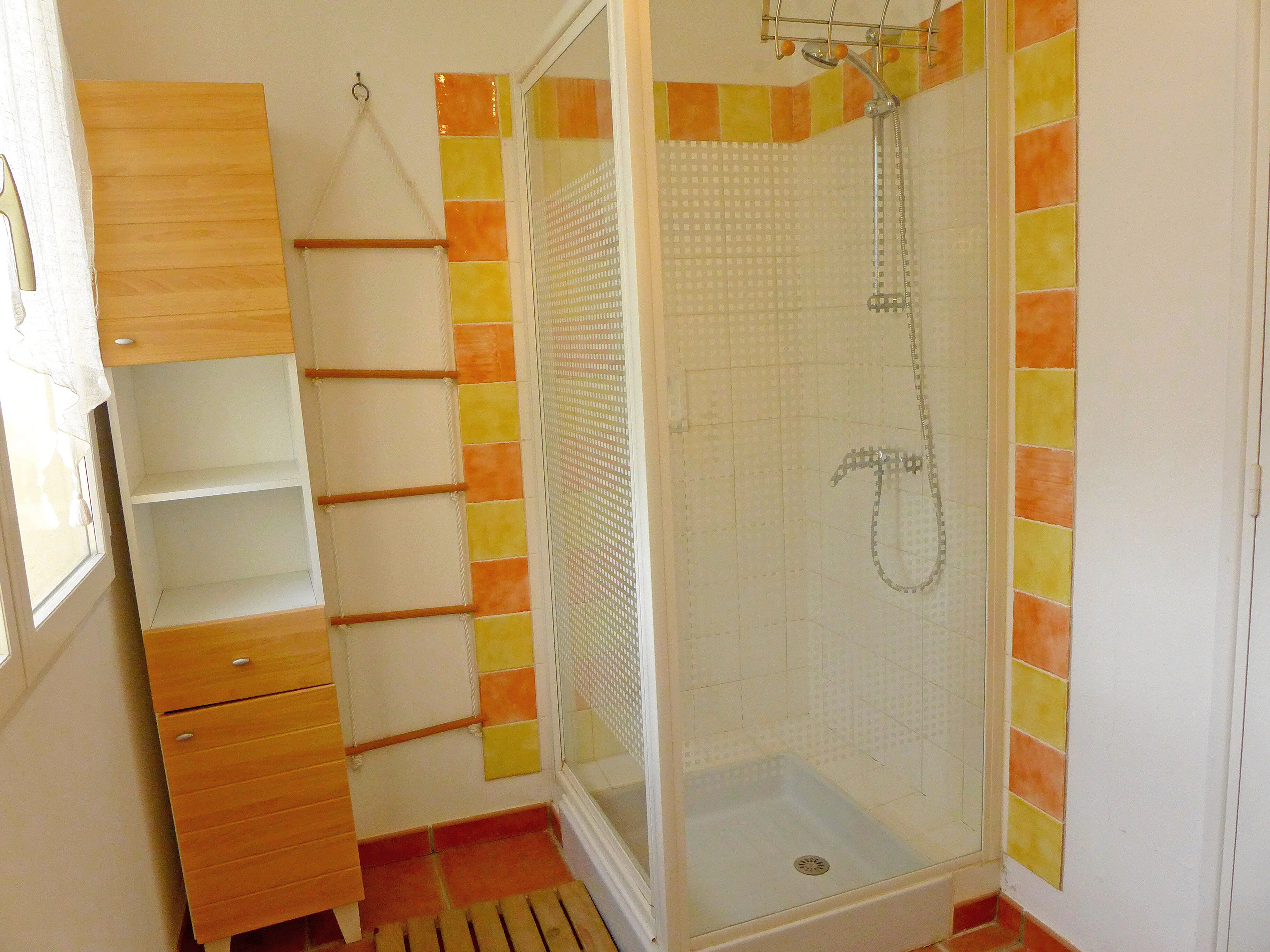 Un baño con ducha, un armario de madera y una pared con azulejos.