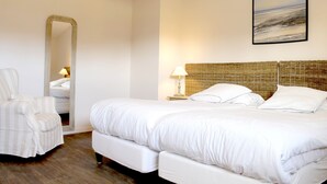 A hotel room with a large bed, a chair, a mirror, and a wall-mounted lamp. - Villa Celtitude - Villas of Sands  (Plurien)