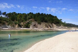 A beach with clear water, sandy shore, and a forested hillside. - Villa Celtitude - Villas of Sands  (Plurien)