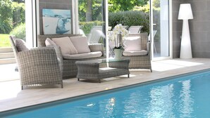 A poolside area with wicker furniture, a glass table, and a lamp. - Villa Celtitude - Villas of Sands  (Plurien)