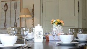 A dining table set with white plates, bowls, and wine glasses, a white container labeled "SWEET HOME COOKIES", and a vase with flowers. - Villa Celtitude - Villas of Sands  (Plurien)