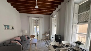 Un salon avec un canapé, une table à manger dressée pour deux personnes et un téléviseur.