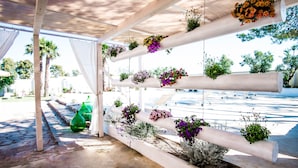 Un espace extérieur abrité, doté de colonnes blanches soutenant des jardinières suspendues.