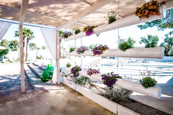 Un espace extérieur abrité, doté de colonnes blanches soutenant des jardinières suspendues.